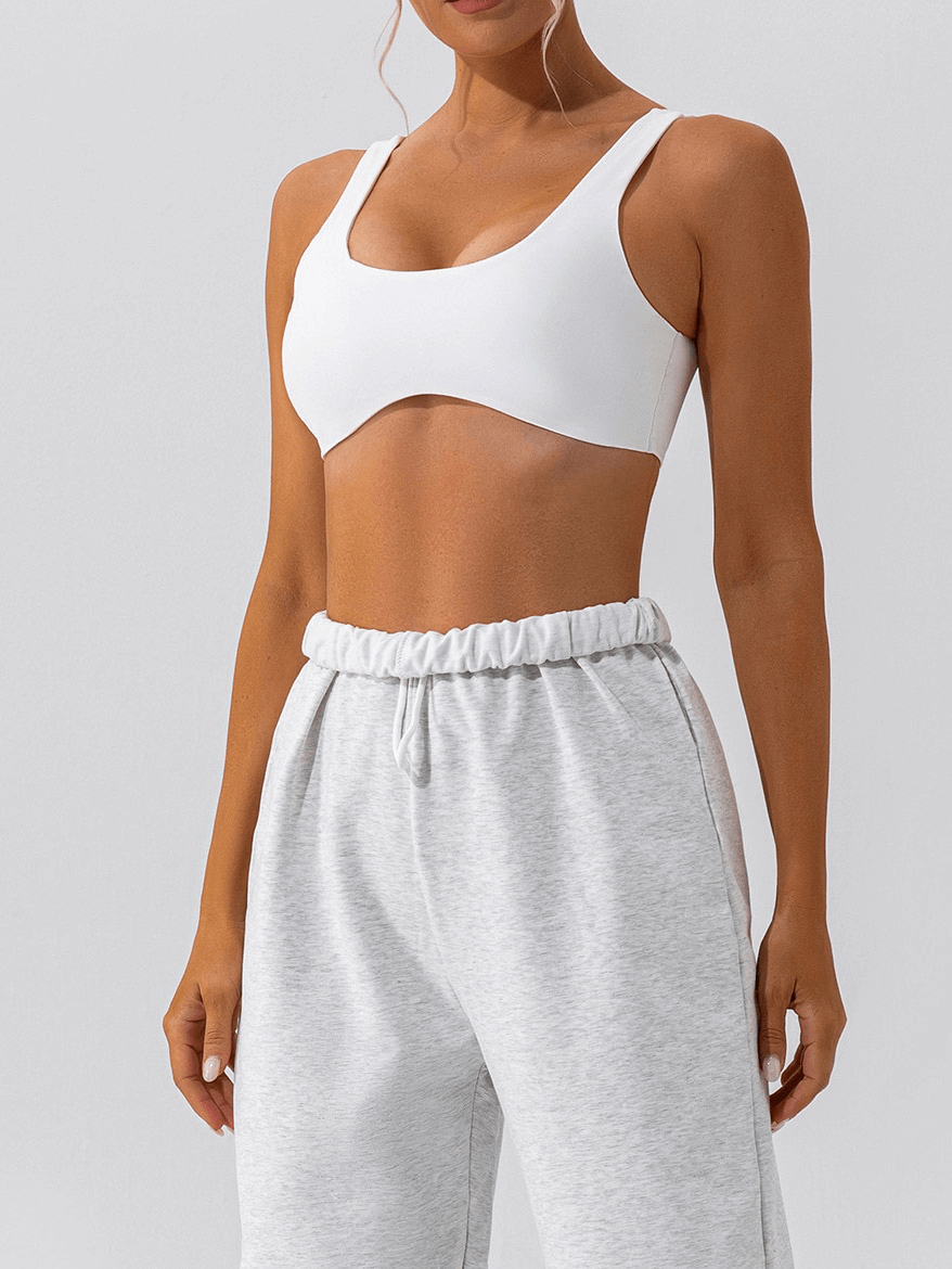 Woman wearing white breathable seamless sports bra and grey pants, ideal for gym workouts and yoga sessions.